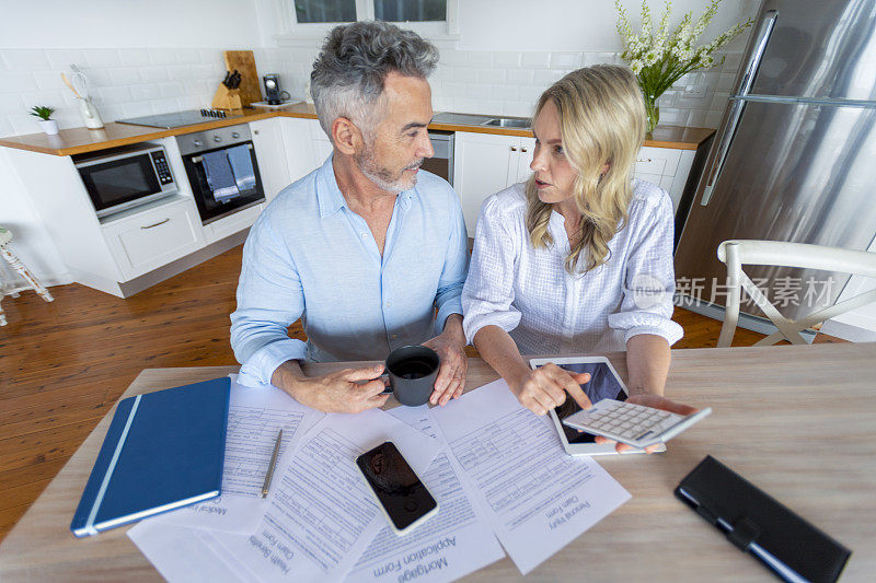 Mature couple doing paperwork and paying bills at home.